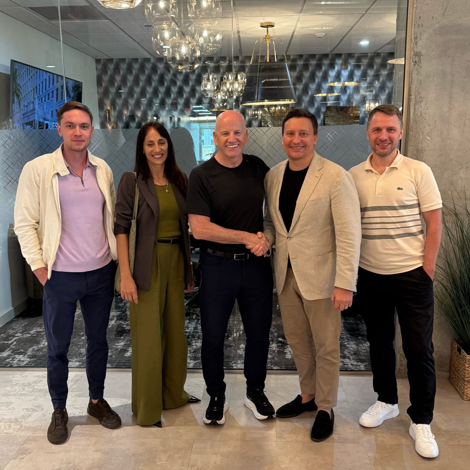 Seán Gallagher shaking hands with Andrey Sokurec, flanked by three Homestead Road colleagues, in the lobby of Homestead Road's Miami office